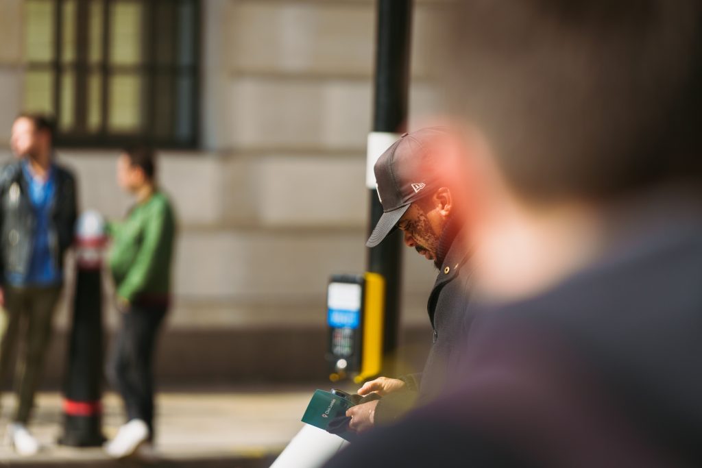 An urban snapshot capturing a man in a cap amidst a bustling city street environment