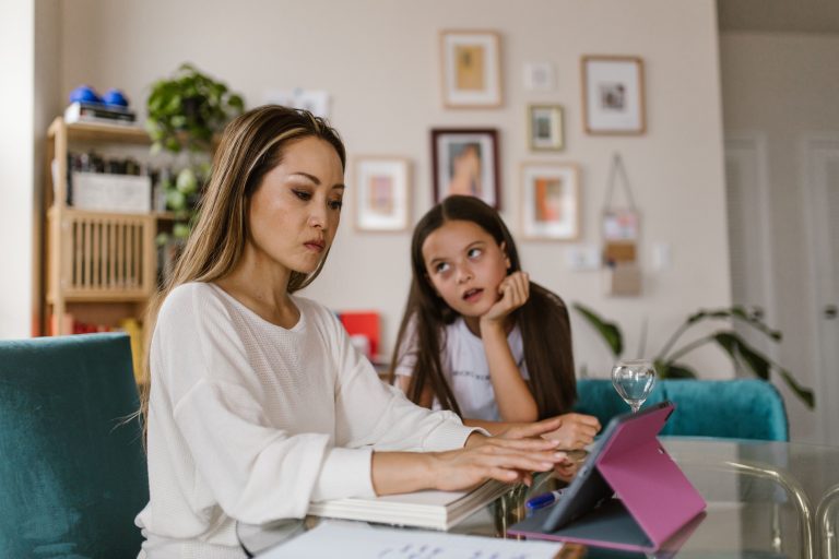 Innovation over Regulation Urged for Families 1 A mother working on her tablet at home while her daughter watches from nearby, illustrating remote work challenges