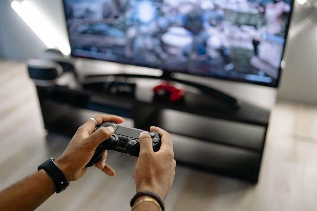 Close-up of hands holding a gaming controller while playing video games indoors