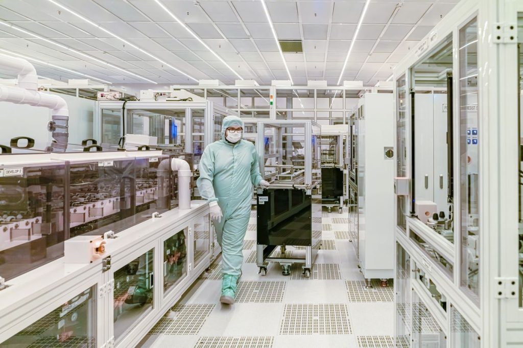 Scientist in protective gear walking in a high-tech cleanroom laboratory environment