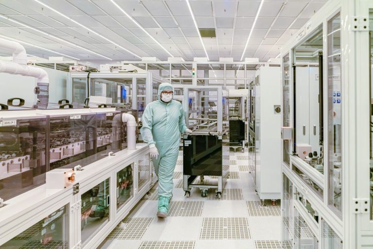 Scientist in protective gear walking in a high-tech cleanroom laboratory environment