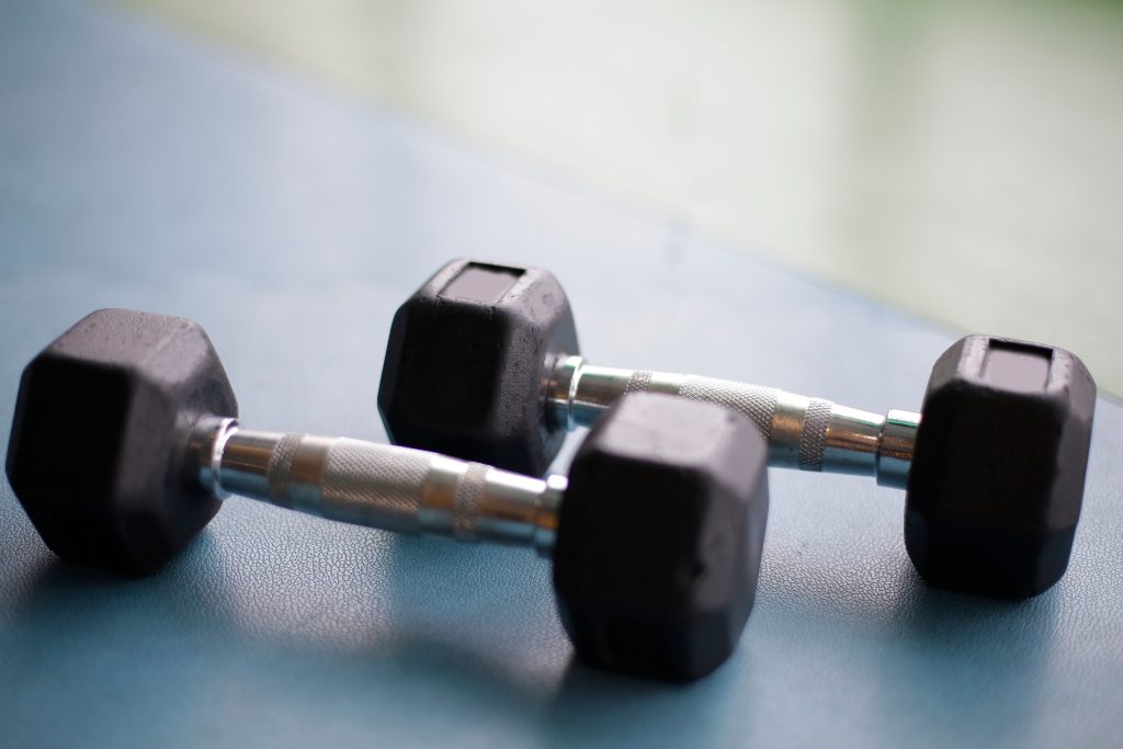 Two black dumbbells resting on a gym floor
