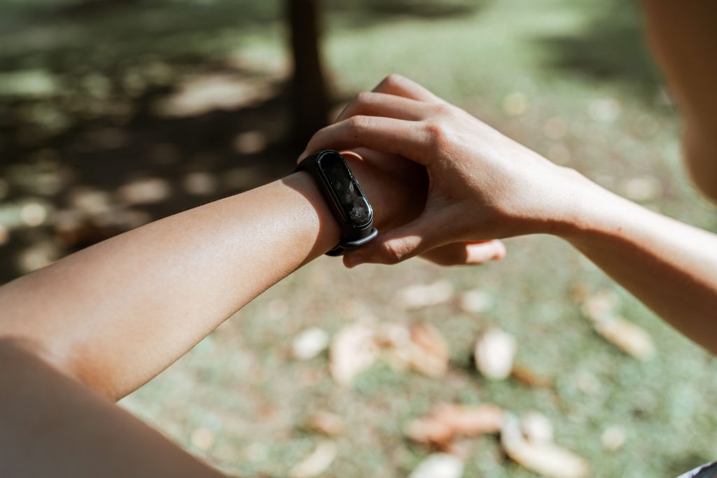 Person checking a black fitness tracker on a wrist outdoors